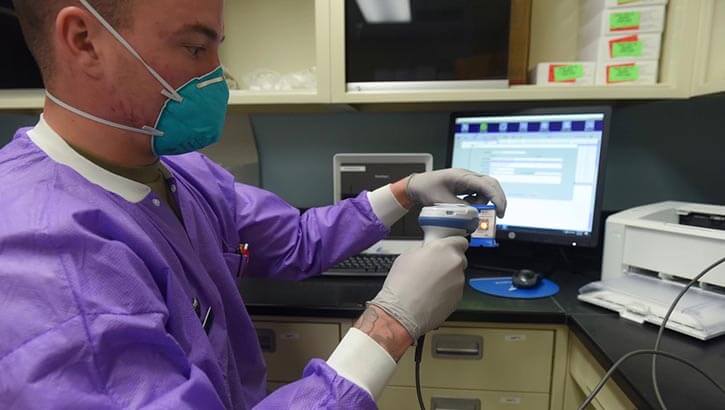 Image of Military personnel preparing a COVID-19 test sample for processing.