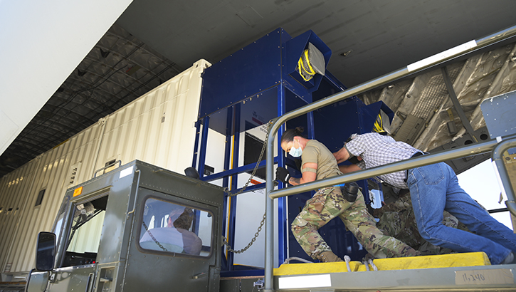 Image of Soldiers in masks pushing a piece of equipment.