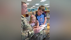 U.S. Army Civil Affairs and Psychological Operations Command Sgt. 1st Class Todd Freeman takes a break from an interview about his music to read a book with his children