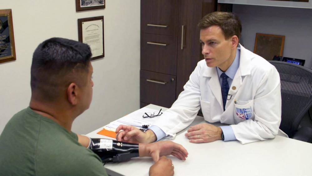 Image of A doctor looks at a patient's prosthetic arm.