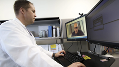 U.S. Air Force Lt. Col. Brendt Feldt, a surgeon at Landstuhl Regional Medical Center’s Ear, Nose and Throat Clinic, conducts a virtual health appointment via synchronous video, April 7, 2020. In a session at the Defense Health Information Technology Symposium, key experts in health care IT discussed how leveraging technology, such as MHS Video Connect, can better connect patients and providers. (Photo: Marcy Sanchez)