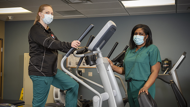 Image of Two military personnel wearing face mask standing on gym equipment.