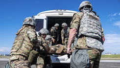 Airmen from the 374th Medical Group lift a simulated patient into a medical transport vehicle during exercise Beverly Morning 24-1 at Yokota Air Base, Japan, Oct. 20, 2023. Securing each affected patient into the medical transport was the final action the Airmen completed before departing the flight line. (U.S. Air Force photo by Airman 1st Class Alexzandra Gracey)