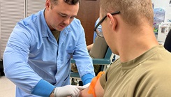 Munson Army Health Center Medical Laboratory Specialist Sgt. Mike Hall checks the veins on a patient’s arm before collecting blood samples