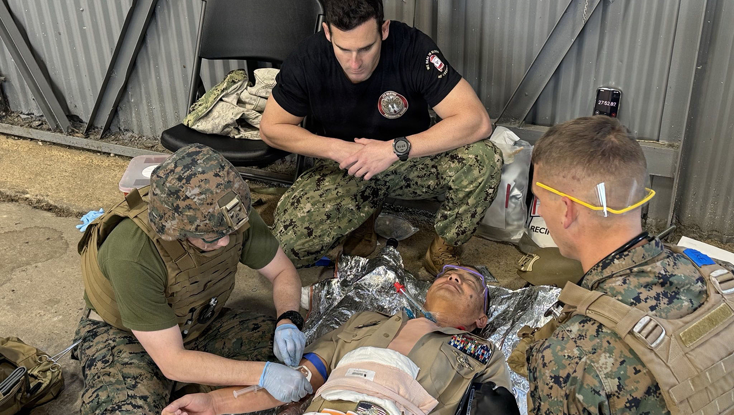 Lt. Cmdr. Ian Eisenhauer and Lt. Cmdr. Ronald Fenton, emergency medicine physicians assigned to II Marine Expeditionary Force (II MEF), perform a simulated autologous fresh whole blood transfusion on Capt. Andrew Lin, commanding officer of Navy Medicine Readiness and Training Command (NMRTC) Fort Belvoir, while Lt. Cmdr. Josh Kotler, command program director, evaluates the team during a Joint Trauma System (JTS) Valkyrie Course