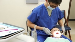 Military health personnel wearing a face mask examines the mouth of a child